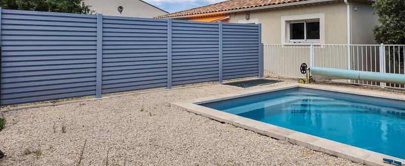 Clôture brise-vue en aluminium à lames en Z autour de la piscine.