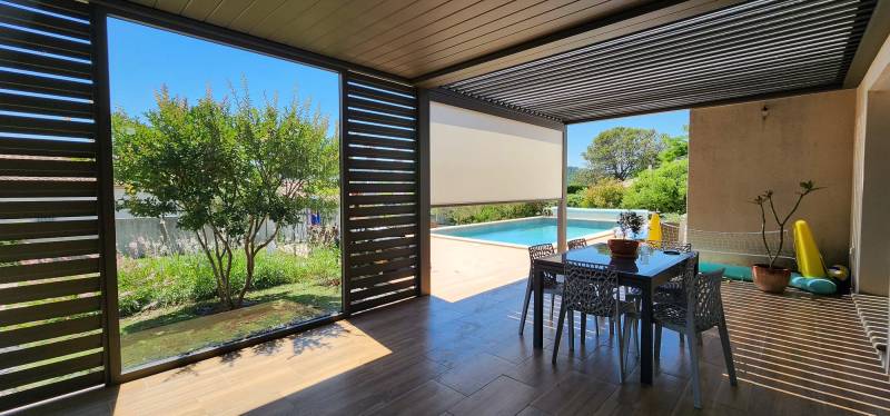 Pergola bioclimatique aluminium avec claustras et store ZIP pour créer une terrasse protégée, ombragée et confortable durablement